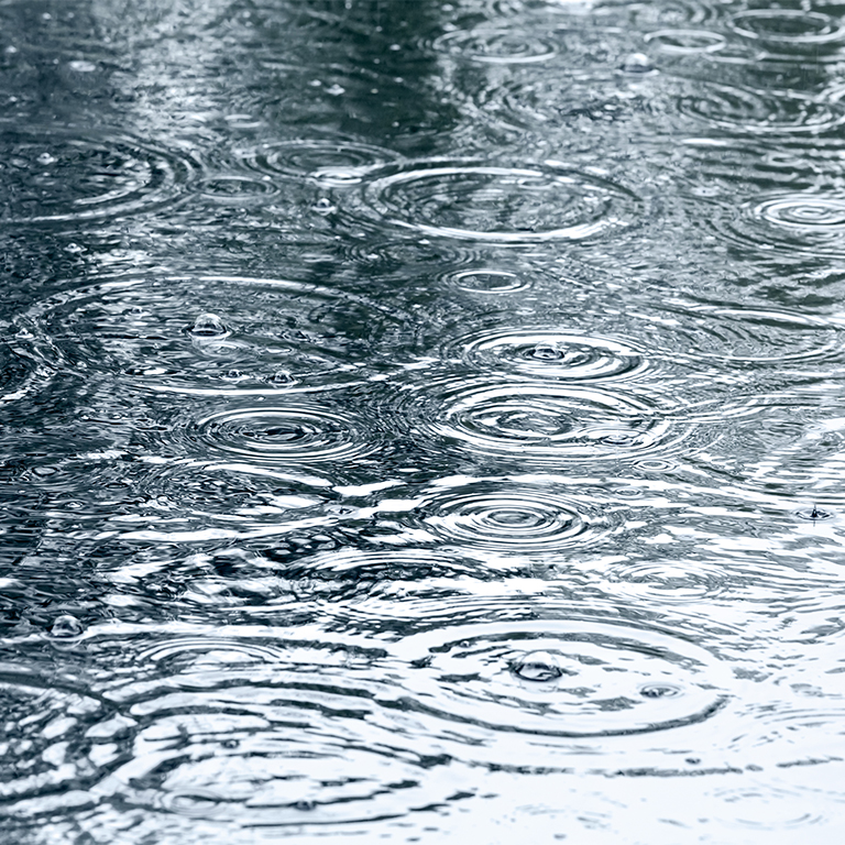 sidewalk with rain drops and ripples in puddles